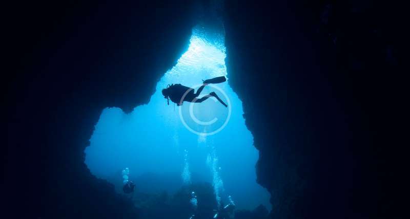 Divers passing through an underwater cave